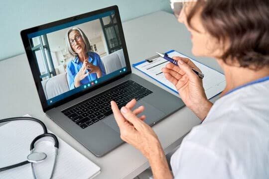 A MyHomeDoc Telehealth doctor on a laptop screen reviewing medical documentation and functional limitations with a patient in Texas for a work or school accommodation letter evaluation.